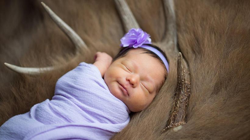 Newborn baby girl next to deer antler