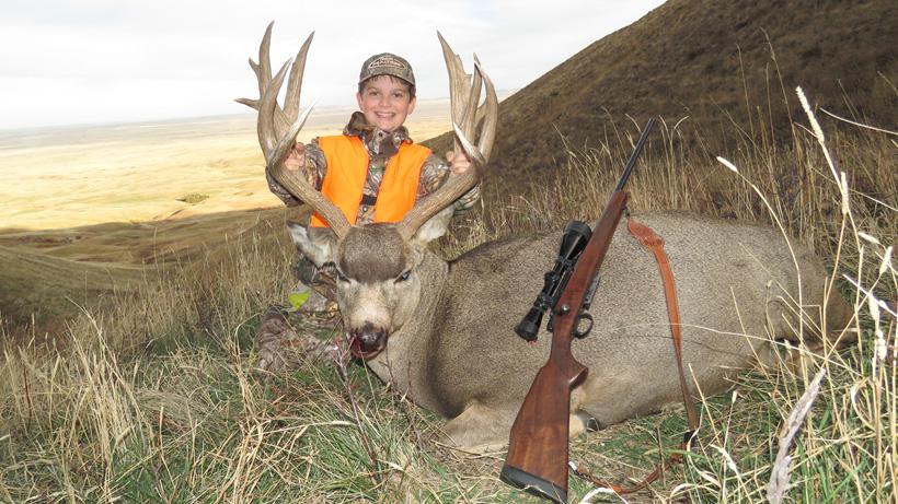 Youth hunter with a massive montana mule deer taken with northern rockies outfitters